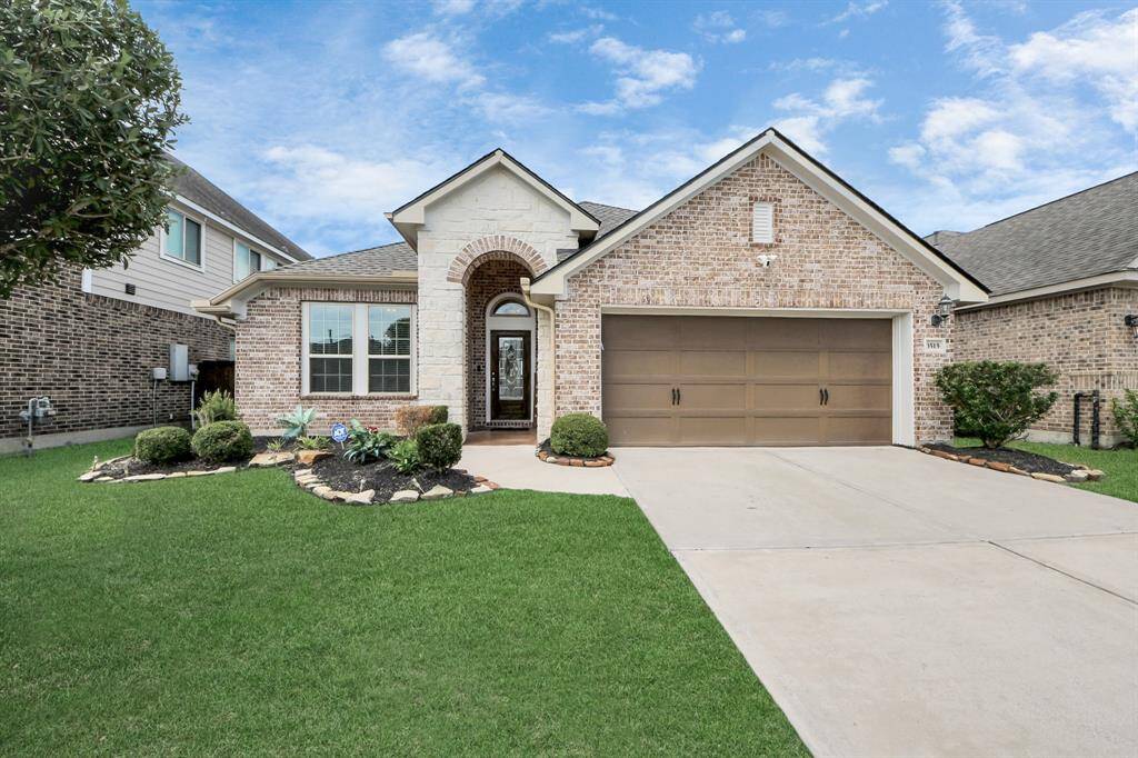 Featuring a welcoming front yard neatly landscaped and a single tree. It has a two-car garage and a spacious driveway, offering a clean and well-maintained exterior.