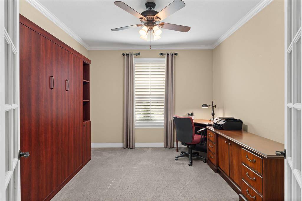 The built-in Murphy bed allows this study to double as a cozy bedroom, with French doors and neutral curtains offering privacy. A perfect space for grandkids to feel right at home during their visits.