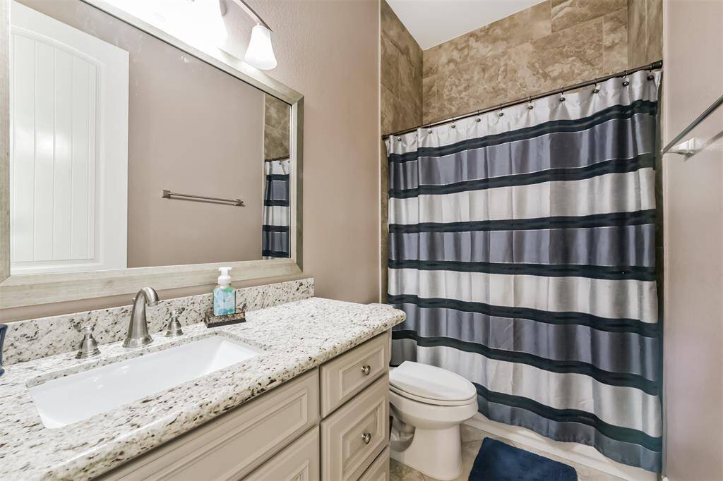 This bathroom features a modern design with a granite countertop vanity and large mirror.. The neutral tones and quality finishes create a clean and inviting space.