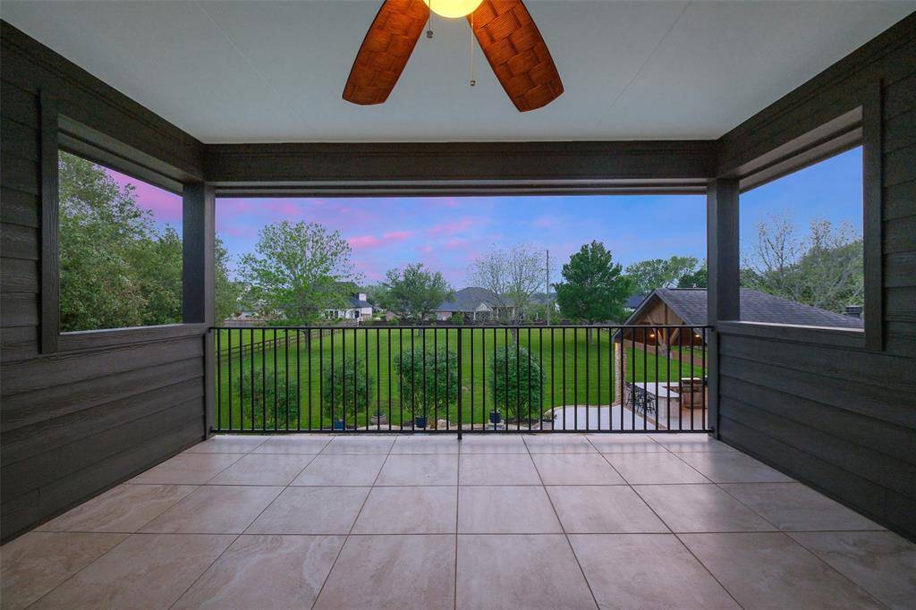 This photo showcases a spacious, covered patio with a ceiling fan, offering a scenic view of a lush green lawn. Perfect for relaxing and entertaining, it provides a serene outdoor space with ample privacy and comfort.