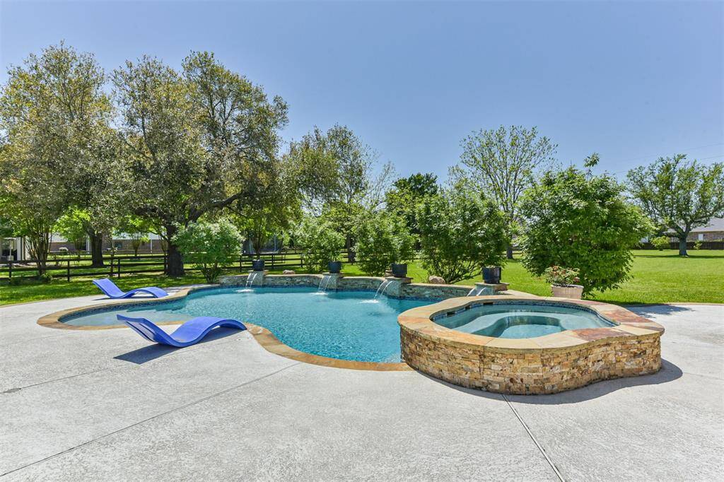 This photo showcases  a luxurious pool and hot tub, surrounded by lush greenery and mature trees, perfect for hot Texas Summer Days and Nights.