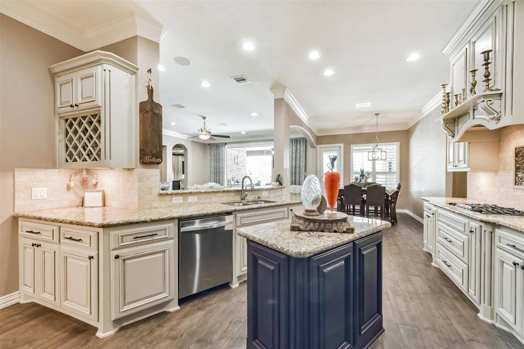 This photo showcases a spacious, elegant kitchen with granite countertops, custom cabinetry, and stainless steel appliances. The open layout flows into a dining area with plenty of natural light, emphasizing a warm, inviting atmosphere.