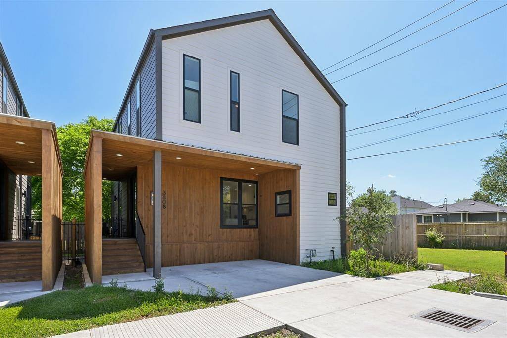 Modern two-story home with a sleek design, featuring a combination of wood and white siding.