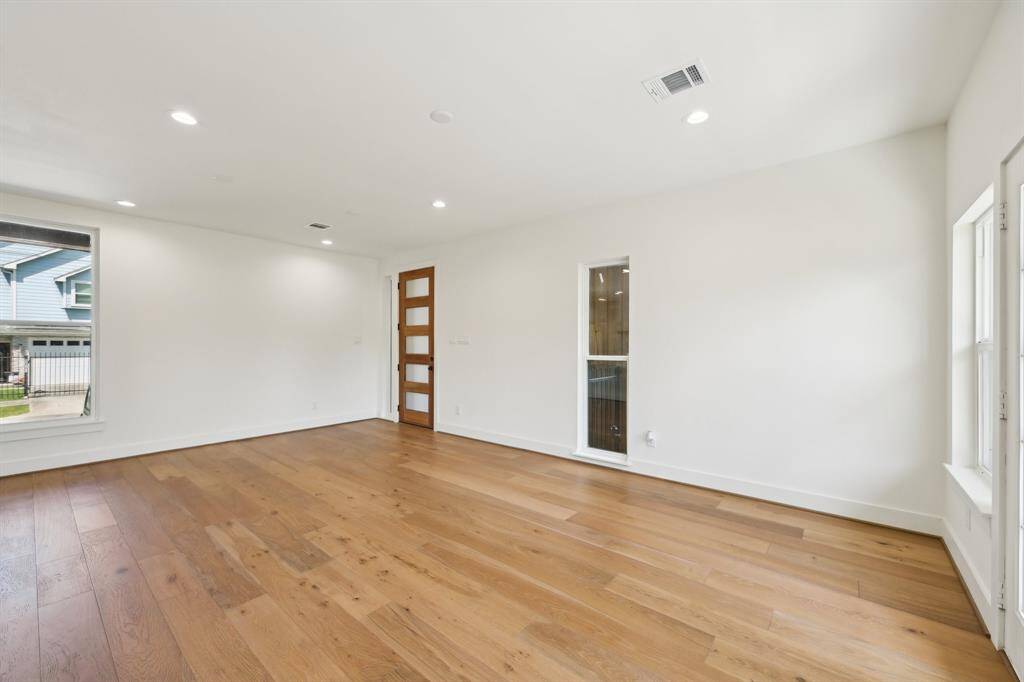 It includes a covered carport, large windows, and a small yard with a wooden fence, offering a blend of style and practicality.