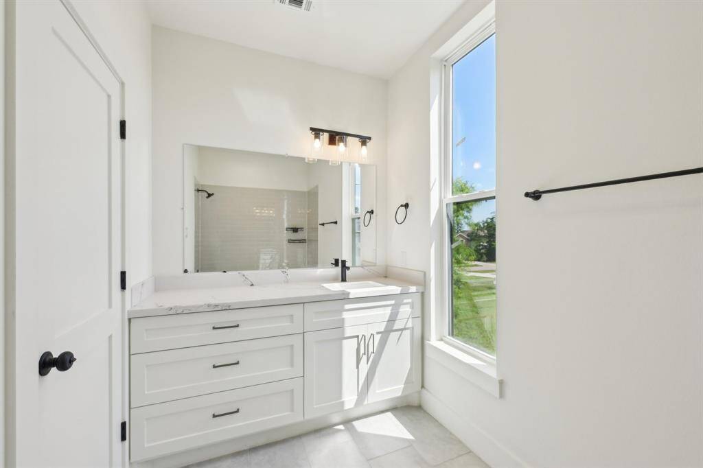 modern bathroom with a large window, white cabinetry, a spacious countertop, and sleek fixtures.