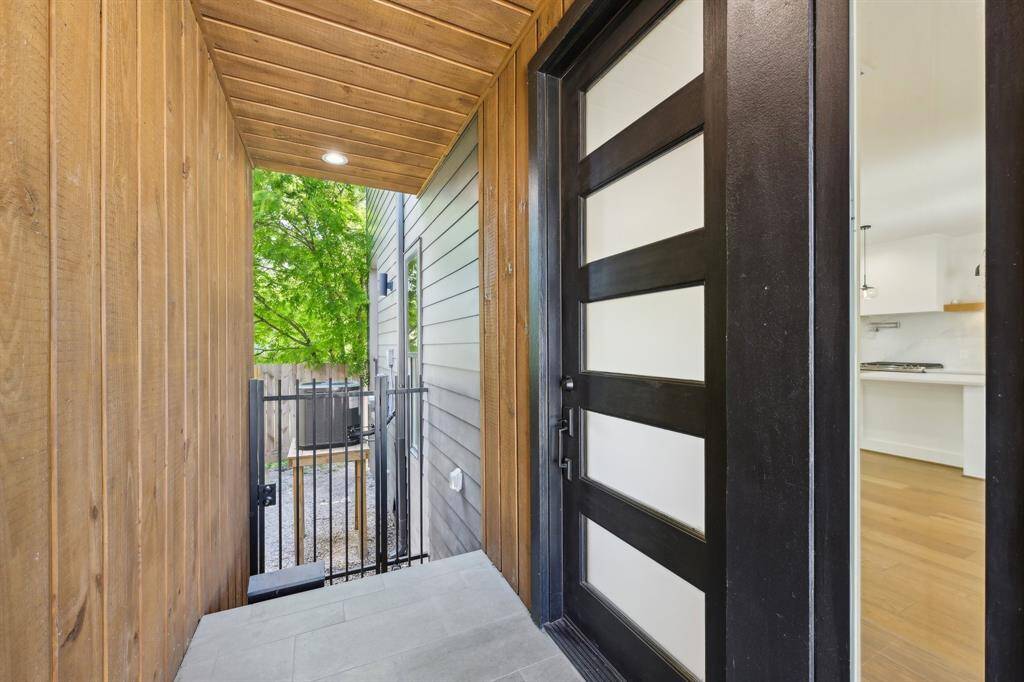 This photo shows a modern entryway with wood paneling and a sleek black door with frosted glass panels.