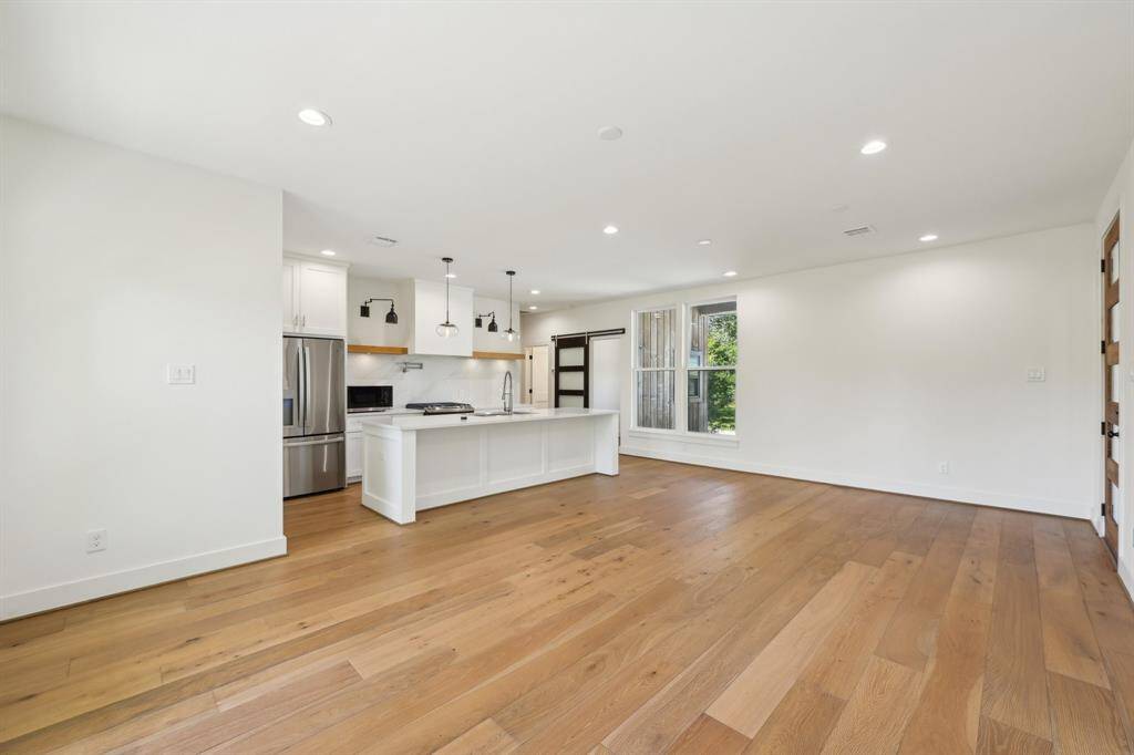 Bright, open-concept living space with hardwood floors, recessed lighting.