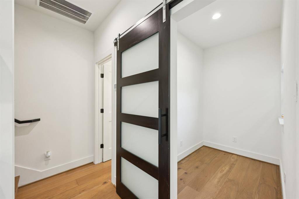 This photo showcases a modern interior space with a sleek sliding door featuring frosted glass panels, light wood flooring, and white walls, creating a bright and contemporary atmosphere.