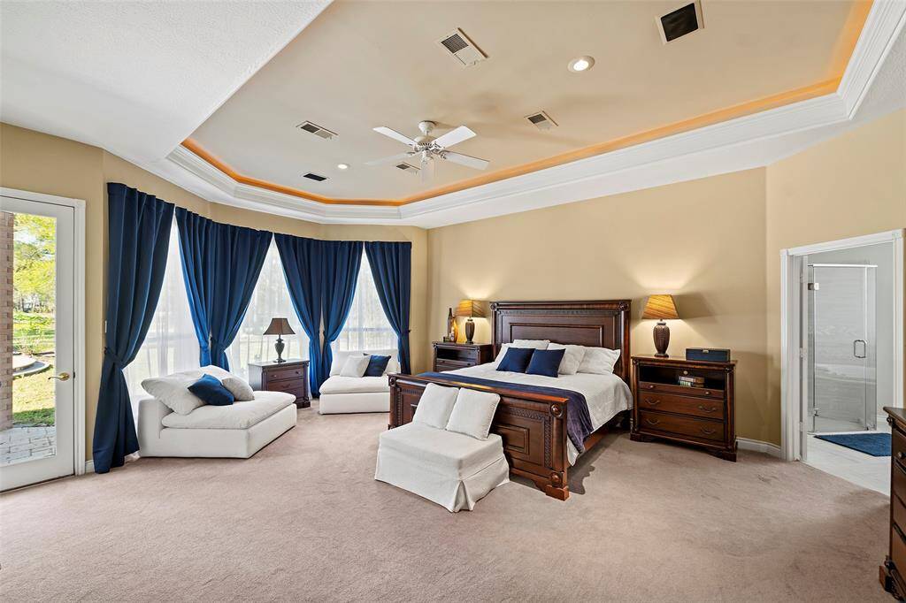Welcome to the serene primary ensuite with ample space for a seating area and a glass door that opens to a wonderful, covered patio overlooking the backyard oasis! Relaxing in the spa or midnight swims may be undetectable with your own private access to this ensuite!