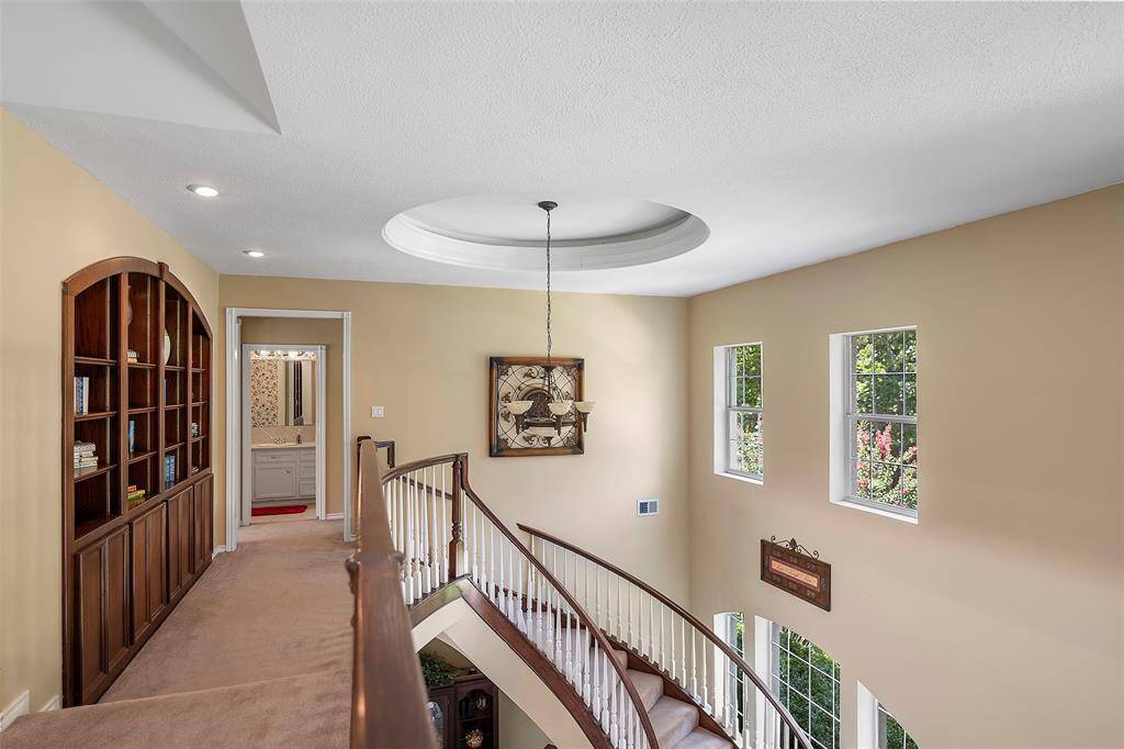 Let's explore the upstairs livings spaces! It is light and bright up here as well with the raised pocket windows that let the light flood into the space! A circle inset for the chandelier is an eye-catcher, and a wall with a pretty arched custom built-in for special displays and photos finishes out the space!