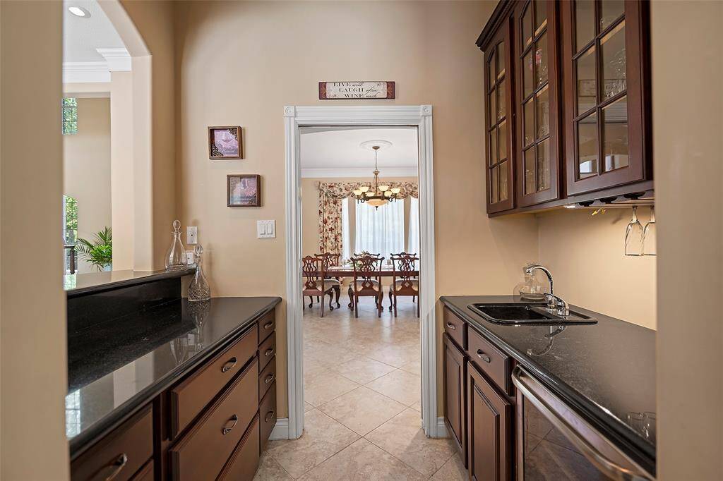 This wet bar is situated with ideal access to the formal dining room and formal living room! Glass front cabinets for display, and drawers for storage, along with a sink and wine refrigerator keeps it all clean and chill!