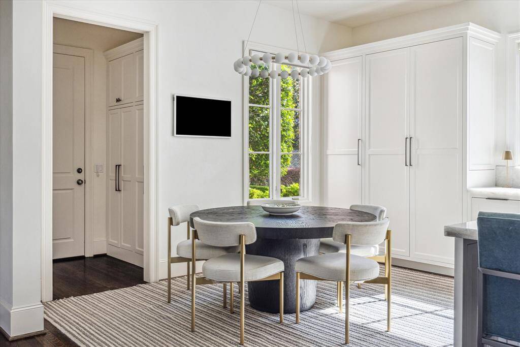 A stylish breakfast nook with custom built-ins and designer lighting sits nearby and is ideal for morning coffee or family breakfasts. A large window fills the space with natural light, highlighting the clean lines and modern finishes, and creating a bright, welcoming atmosphere throughout.