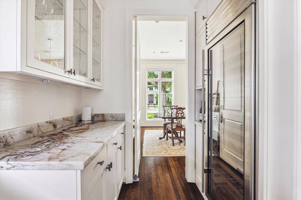 Just off the kitchen, a well-appointed butler’s pantry features the same stunning Taj Mahal quartzite counters and offers seamless access to both the dining room and kitchen, making entertaining effortless. Adjacent is a spacious walk-in pantry and full size wine cooler, providing ample storage for everything from everyday essentials