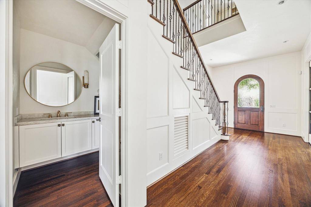 Remodeled in 2021, this elegant powder bath features Venetian plaster walls and ceiling, Hudson Valley lighting, brass fixtures, and a sleek quartzite vanity tucked just off the entry.