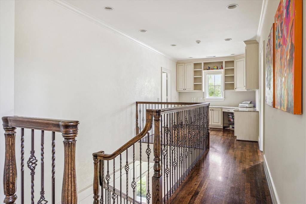 Ideal for work or homework space, the upstairs landing features hardwood floors, wrought iron railings, and a built-in study nook with custom cabinetry and natural light.