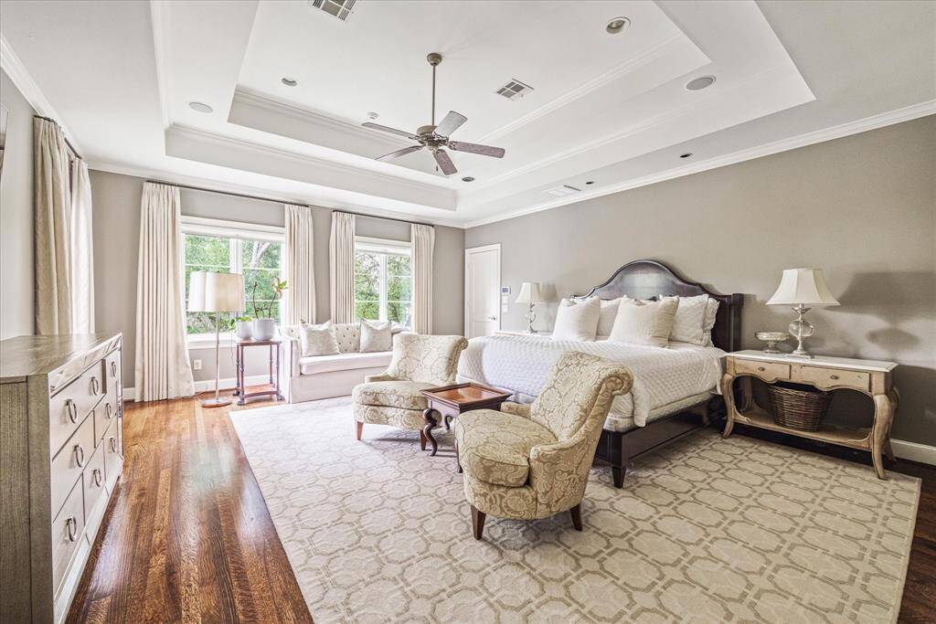 A bright and serene retreat, the primary suite is filled with natural light from the triple windows and highlighted by an elegant stepped ceiling that adds architectural interest. It features two spacious walk-in closets, offering ample storage and organization.