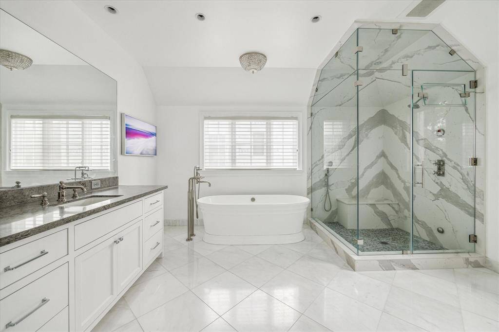 Completely remodeled in 2020, the luxurious primary bath features a freestanding Victoria+Albert soaking tub, an oversized steam shower with book-matched marble, dual vanities, Arcade plumbing fixtures, and sleek tile flooring.