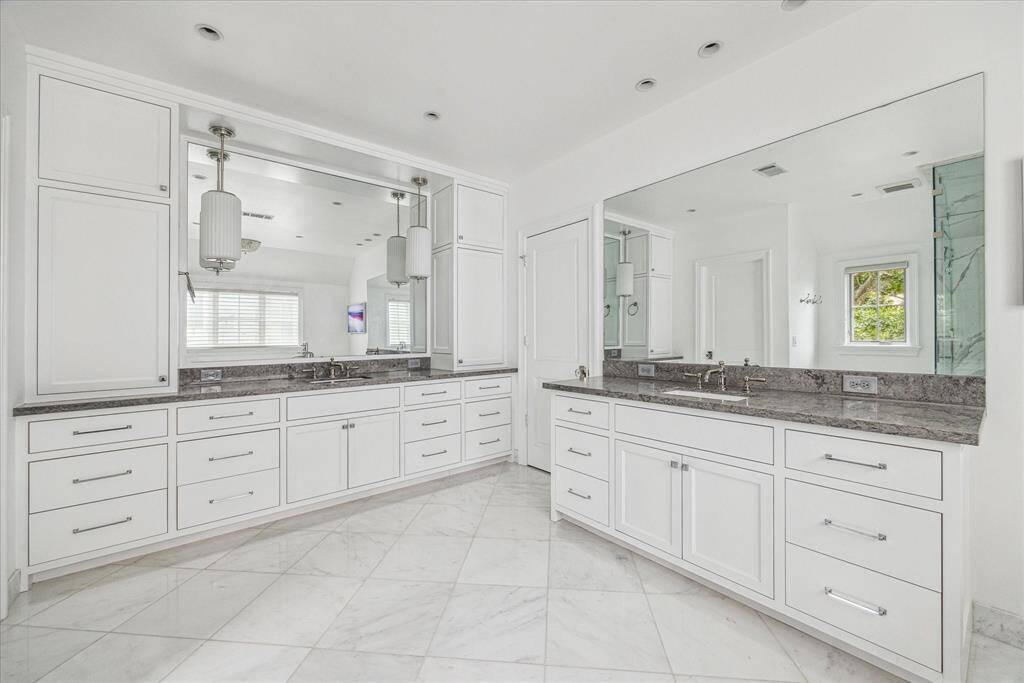 The spacious primary bathroom features dual vanities, ample storage, and elegant Williams Sonoma pendant lighting, offering both style and practicality. Sleek cabinetry provides plenty of space to keep everything organized, while the freestanding Victoria+Albert soaking tub and corner frameless steam shower add a luxurious touch to this bright retreat.