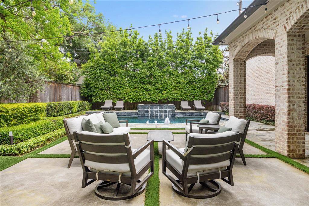 The inviting outdoor living space proudly boasts a serene pool and spa as the focal point and is surrounded by lush greenery and privacy hedges. Nearby, large pavers create a space for lounging, dining, or gathering with friends and family. The layout is thoughtfully designed to maximize both relaxation and functionality, making it an ideal outdoor retreat for warm days and lively evenings alike.