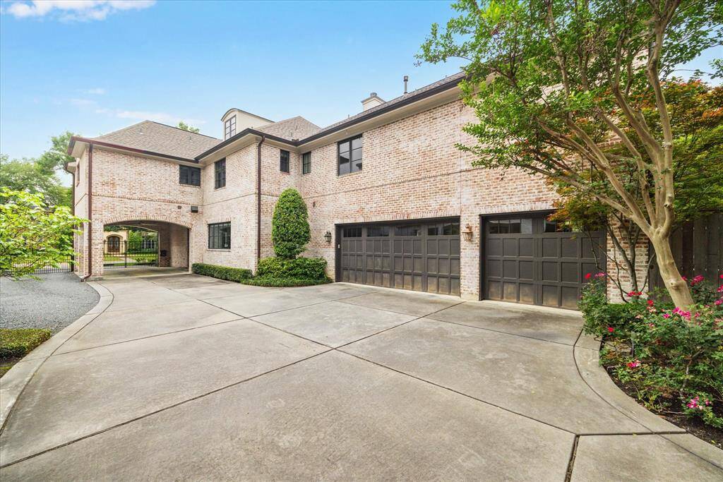 A drive-through gate leads beneath a stately porte-cochère and into a spacious driveway, offering both elegance and functionality. The generous layout provides plenty of room to park and easily maneuver multiple vehicles, making everyday access and guest arrivals smooth and convenient.
