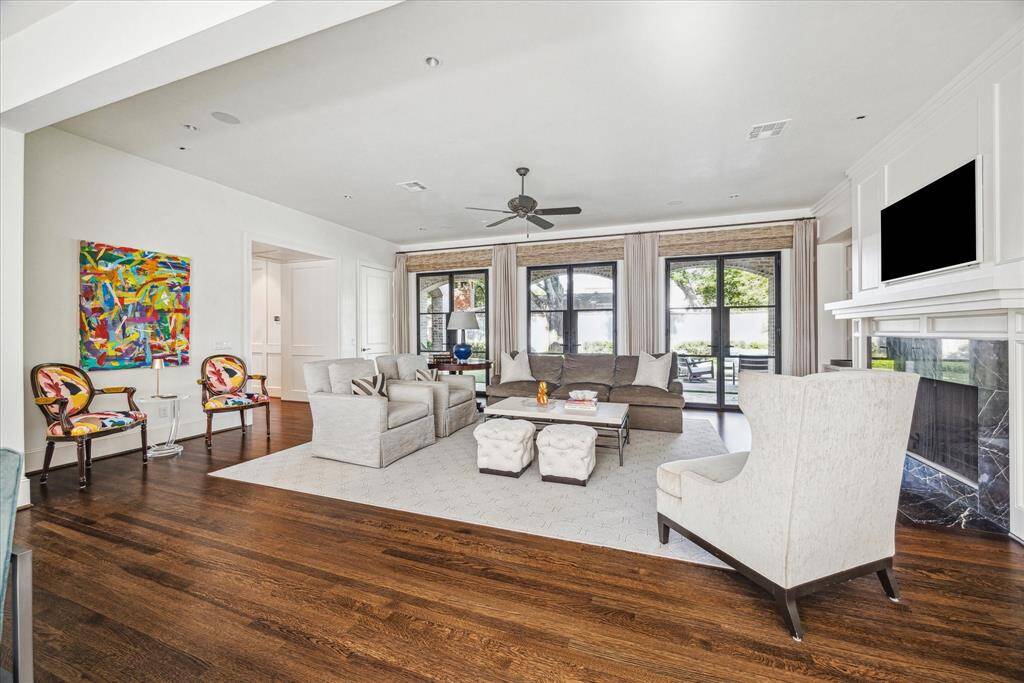 Spacious and sunlit, the family room features rich hardwood floors, a fireplace with custom stone surround, and steel-framed doors that grant access the private side yard—perfect for relaxed indoor-outdoor living.