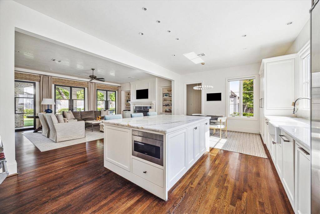 The airy, light-filled kitchen is both stylish and functional, featuring an oversized Taj Mahal quartzite island with bar seating that connects seamlessly to the living space—perfect for casual meals or entertaining guests. The built-in microwave, fireclay farmhouse sink, and soft-close drawers and cabinets add to the kitchen’s functionality.