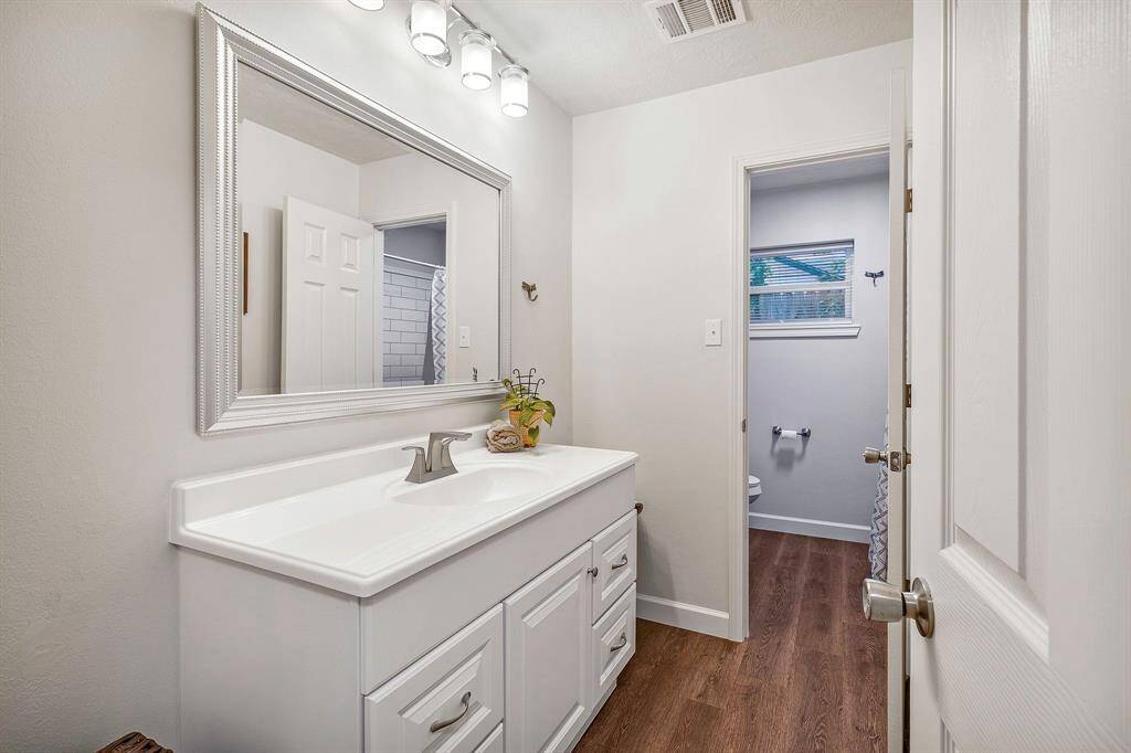 Guests/Secondary bathroom has a modern vanity with ample storage, a large mirror, and elegant lighting **403 E Lake Drive, Livingston, TX 77351**