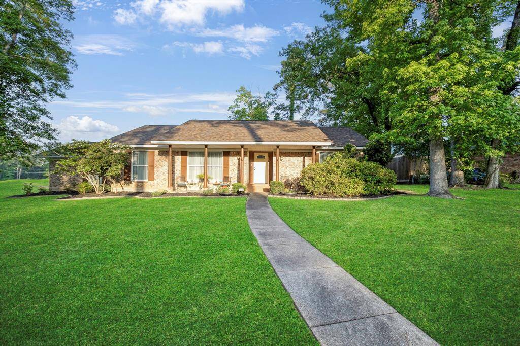 Charming single-story brick home with a welcoming front porch, set on a spacious lawn with mature trees. **403 E Lake Drive, Livingston, TX 77351**
