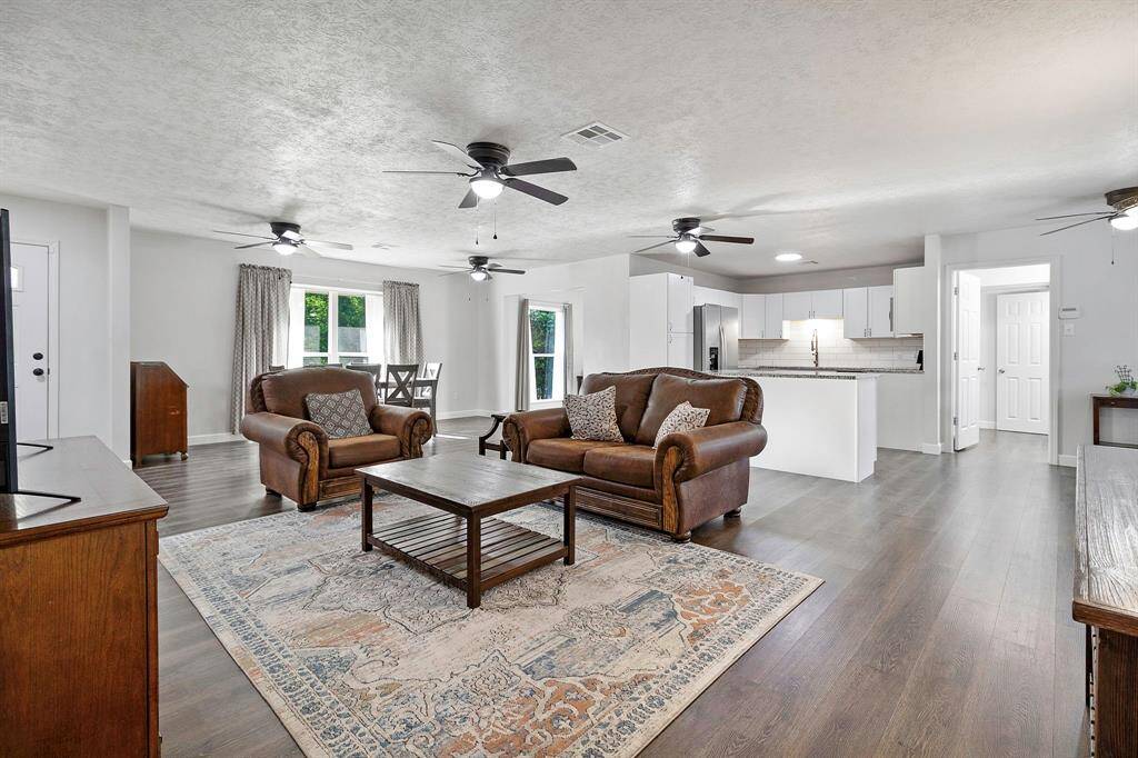 A spacious open concept living area with modern finishes, luxury vinyl flooring, a dining space, and a bright kitchen with white cabinetry and stainless-steel appliances. **403 E Lake Drive, Livingston, TX 77351**