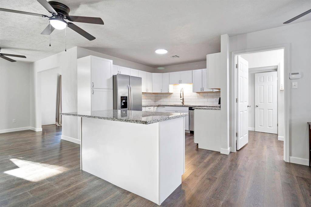 Your modern kitchen features sleek white cabinetry, granite countertops, and stainless-steel appliances. It has an open layout with ample natural light and wood flooring, creating a welcoming and functional space. **403 E Lake Drive, Livingston, TX 77351**