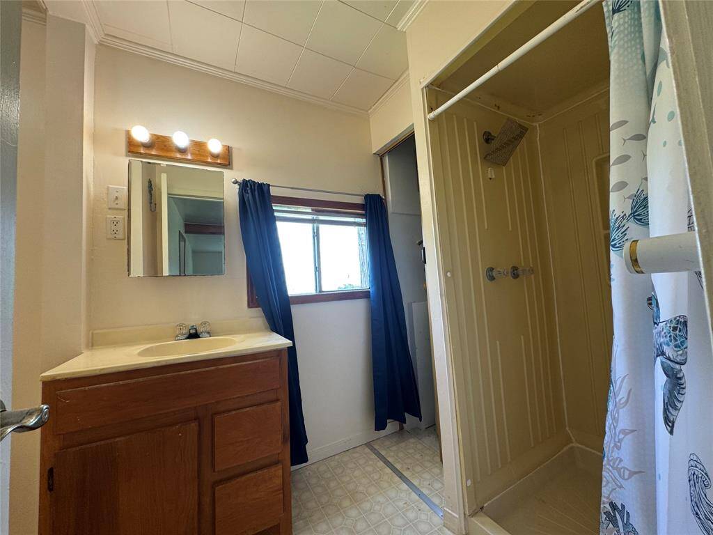 The bathroom features a full-entry shower, a functional vanity with a sink, and convenient under-cabinet storage—combining comfort and practicality in a clean, efficient layout.