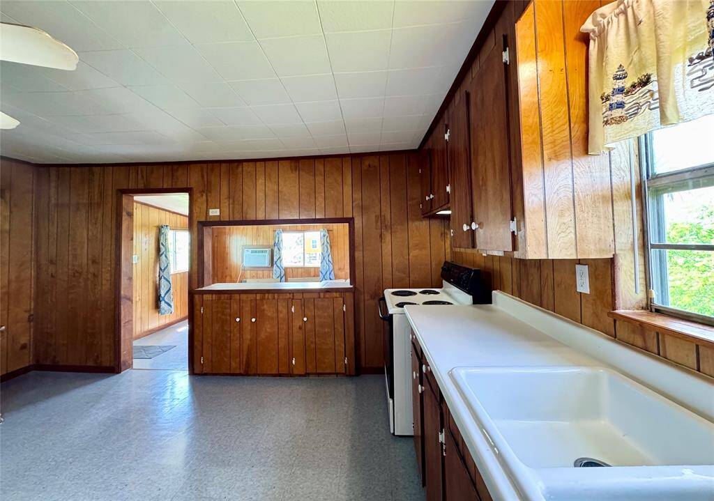 The spacious kitchen offers both functionality and charm, featuring an electric oven, rich wooden walls, a bright window for natural light, and ample cabinet space to keep everything organized and within reach.