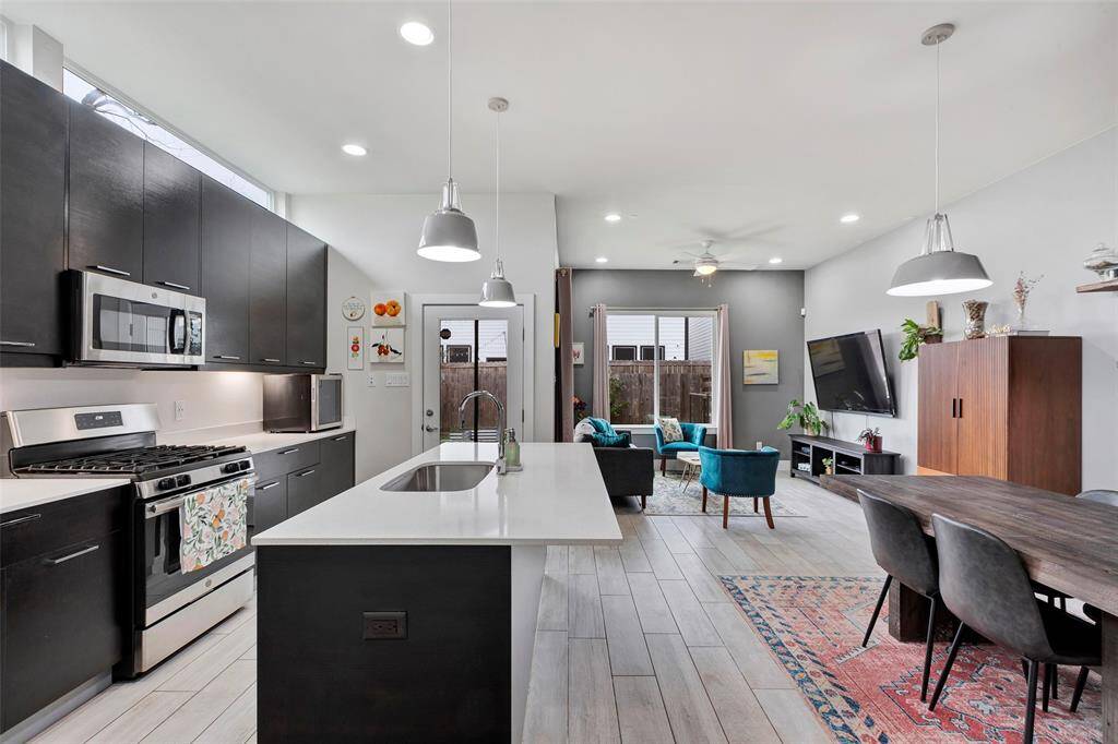 An open view from the foyer – seamlessly connecting the kitchen, dining area, and living room, with the fenced backyard framed perfectly through the expansive glass windows.