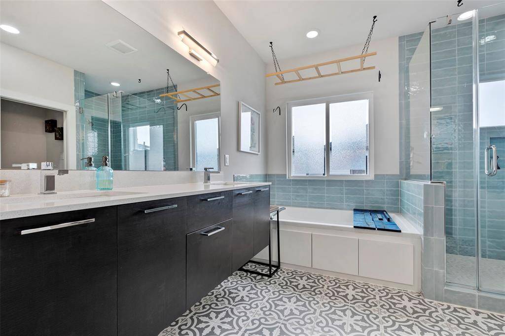 Relax and unwind in the en-suite primary bathroom, featuring calming white and light teal wall tiles that create a serene, spa-like atmosphere.