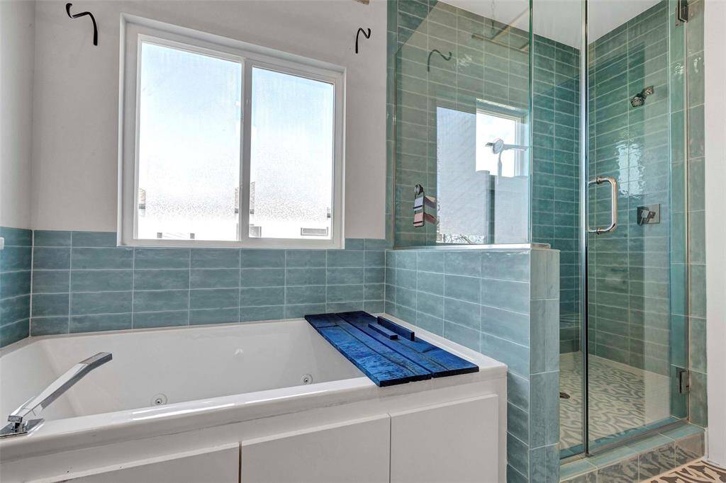A spacious, glass-enclosed shower paired with a luxurious bathtub, offering the perfect setting for ultimate relaxation.