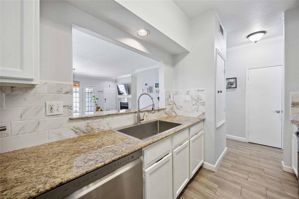 Renovated kitchen with granite countertops, backsplash, and modern appliances.