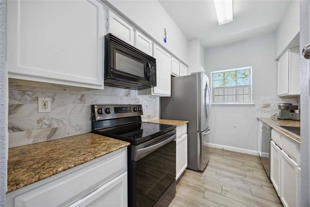 Renovated kitchen with granite countertops, backsplash, and modern appliances.