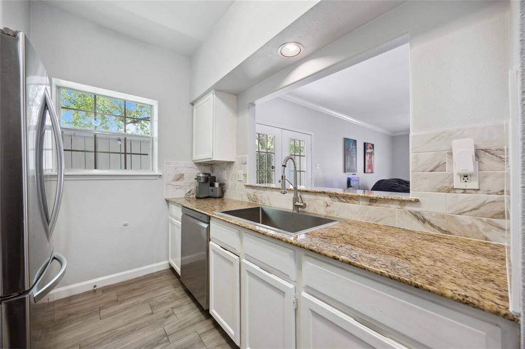 Renovated kitchen with granite countertops, backsplash, and modern appliances.