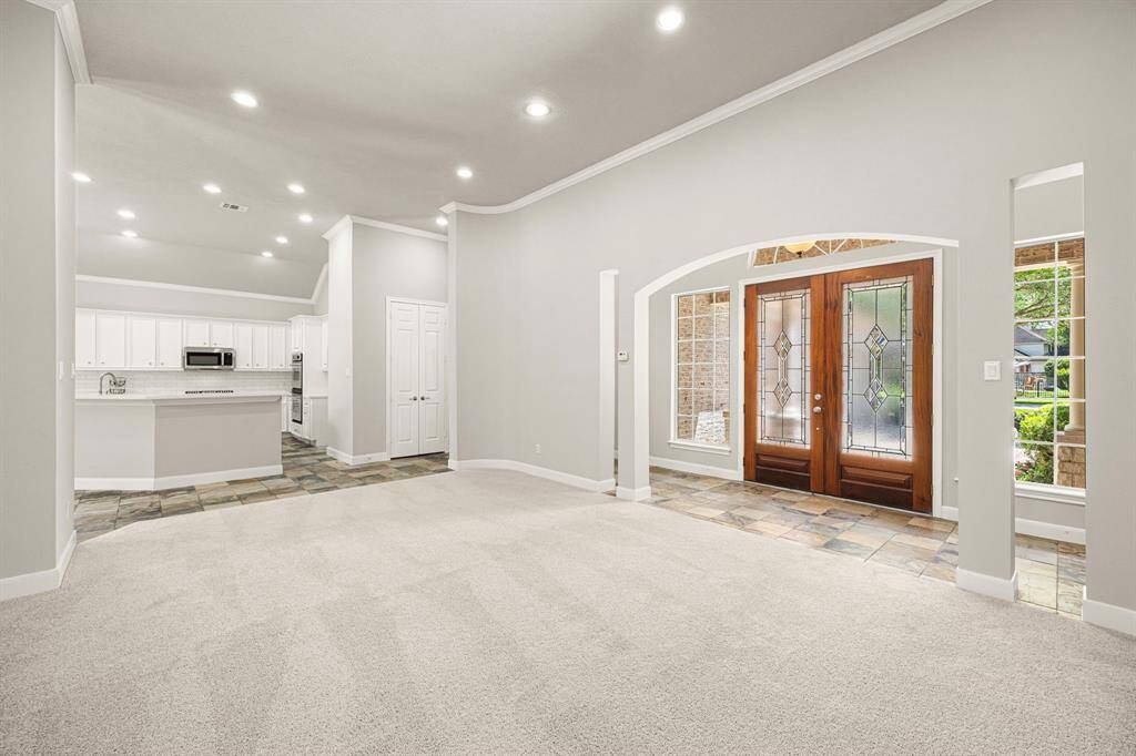 This view looks toward the front Foyer with soaring 12-foot ceilings and an abundance of recessed lighting, creating a bright and welcoming atmosphere.