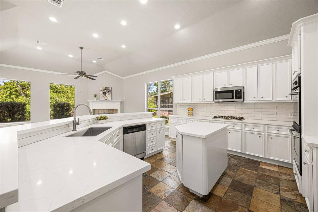 The Kitchen is gorgeous, featuring newly installed Quartz countertops with a 3x9 glass backsplash, fresh paint, and beautiful slate flooring.
