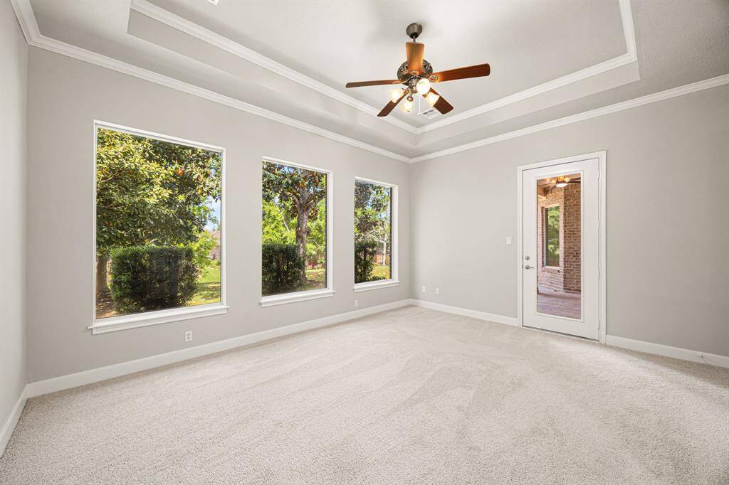 The Primary Suite is privately tucked away at the back of the house and features a 10-foot trey ceiling, newly installed carpet, fresh paint, crown molding, a wall of windows with views of the backyard, and a glass door leading to the covered back Patio.