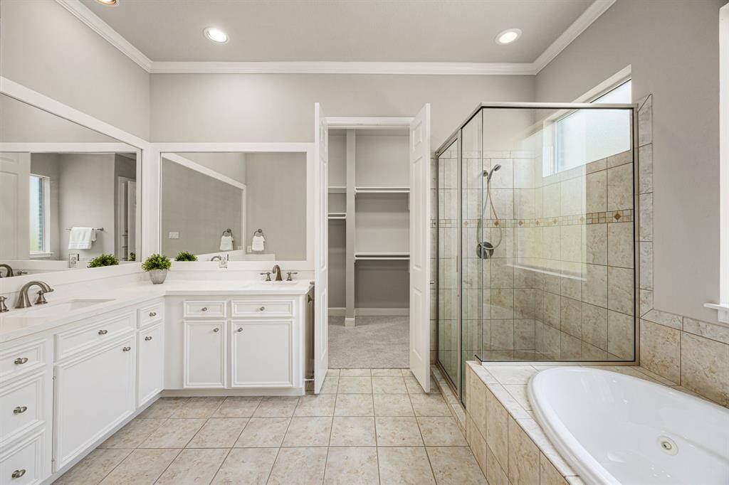 The Primary Bath is luxurious, featuring newly installed quartz countertops with two undermount sinks, fresh paint, and framed mirrors. A jetted tub sits beneath a privacy window, and there’s a separate shower with a handheld wand for added convenience. The walk-in closet is spacious, complete with shelving and built-ins.