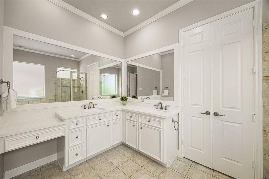The L-shape vanities provide ample space for two, along with a built-in makeup counter for added convenience. The double doors lead to a spacious walk-in Closet.