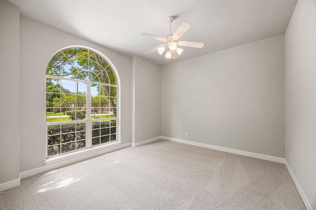 All Secondary Bedrooms are generous in size, each with access to a Full Bath. They feature fresh paint, newly installed carpet, and ceiling fans for added comfort. This bedroom is located at the front of the house and features a picturesque arched window overlooking the beautifully landscaped front yard.