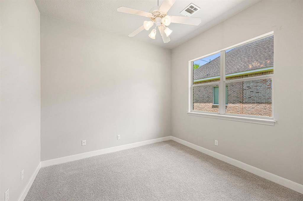 This Secondary Bedroom is on the opposite of the house and features newly installed carpet, fresh paint, a large window for natural light, and a ceiling fan for added comfort.