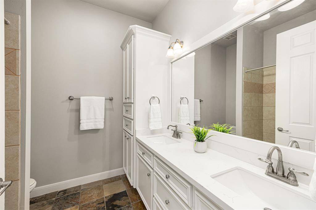 This Full Bath serves the Bedrooms in the previous two photos, featuring Quartz countertops, 2 undermount sinks, satin nickel light fixtures and faucets, slate flooring, a tub/shower combination, and newly painted cabinets.
