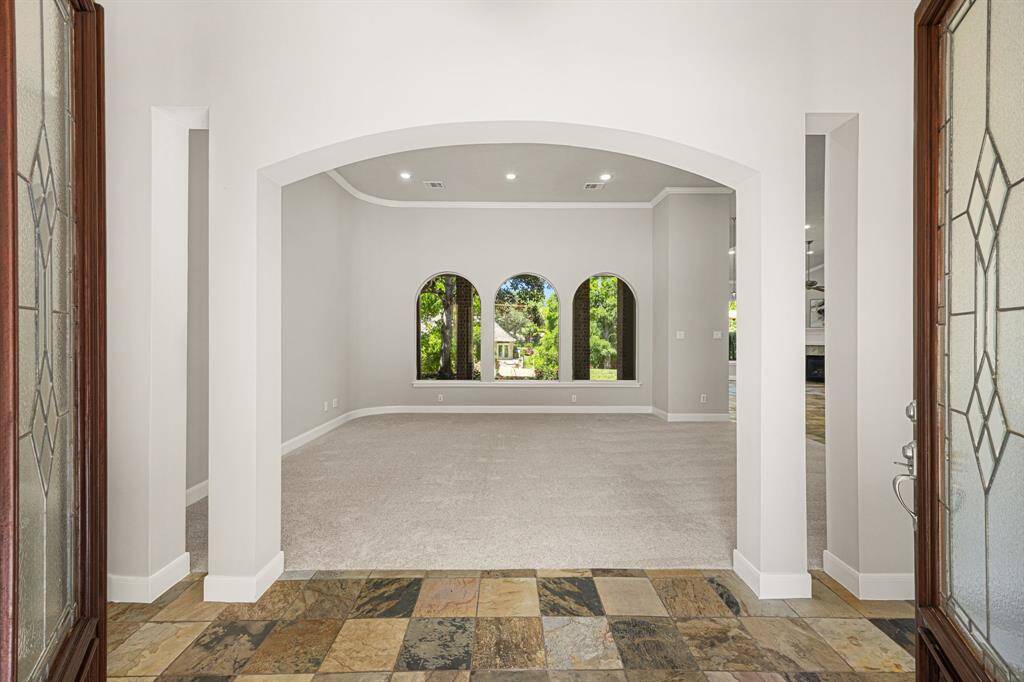 As you enter, you’re greeted by beautiful slate flooring, and your eye is immediately drawn through the archway to a trio of butted windows in the Formal Living Room or Flex Room, offering a stunning view of the Backyard.