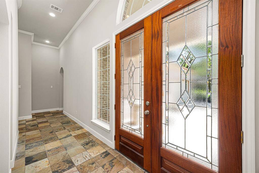 A closer look at the leaded glass double front doors reveals elegant side windows and a transom window above, allowing natural light to flood the entryway.