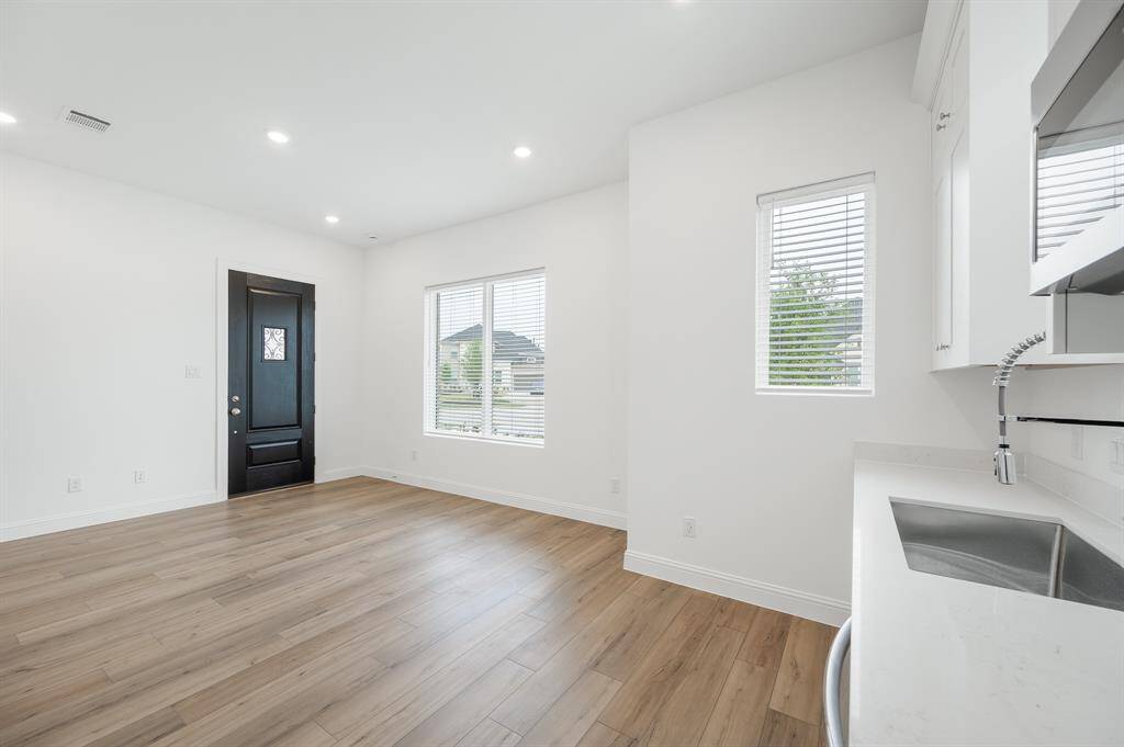 Next Gen® Suit features separate entrance, bright, open living space with light wood look flooring and a modern kitchen. Features large windows for natural light and a sleek black front door. Ideal for a cozy and inviting home atmosphere.