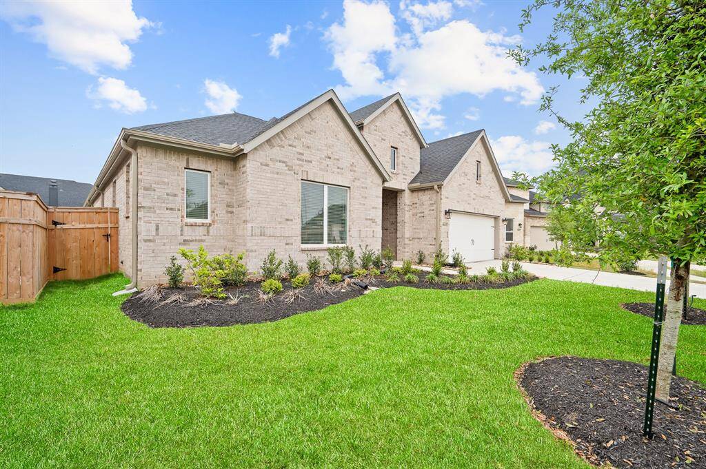 Charming brick home with a modern design, featuring a well-maintained front yard and landscaped garden beds. The property includes a two-car garage and a wooden fence for added privacy. Perfect for those seeking a welcoming suburban feel.